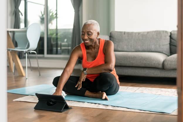 Image_Senior-woman-seated-on-a-yoga-mat-in-a-living-room-looking-at-a-tablet-computer. Create campaign impact by reaching the Workday Consumer